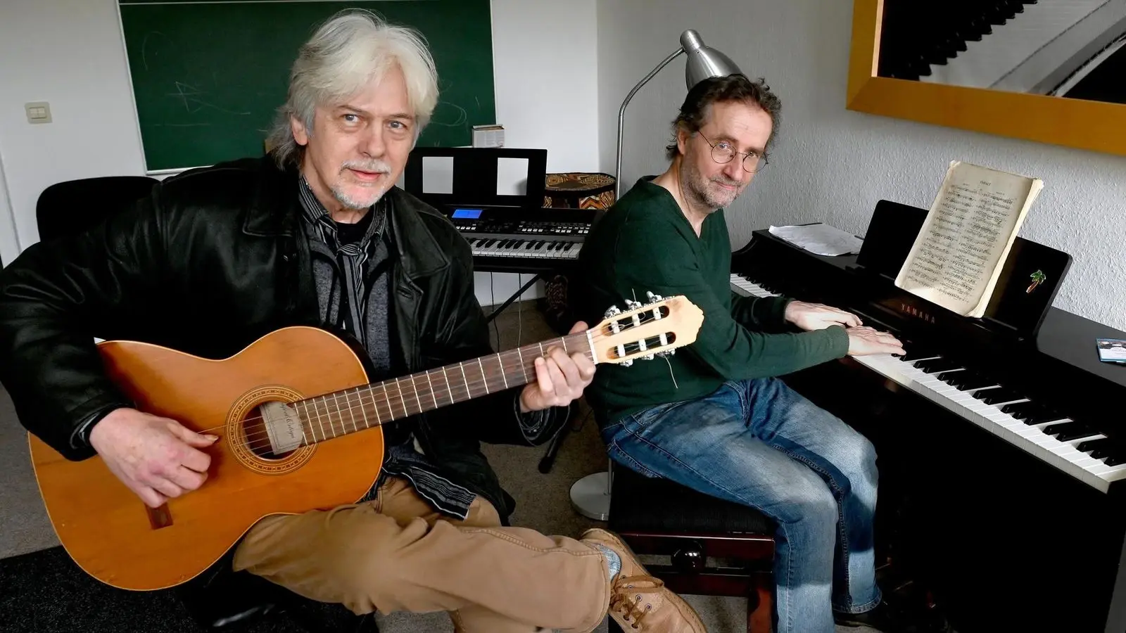 Peter Büschel (links) gibt in der Wolfsburger Musikschule „Musikult“ Gitarren-Unterricht, während Leiter Konrad Brinckmeier Schülern das Klavierspielen beibringt.